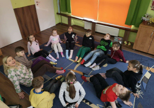 Uczniowie z klasy1b siedzą w kole pokazując różnokolorowe skarpety