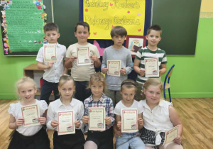 Uczniowie klas 1 trzymają dyplomy za udział w szkolnym konkursie "Pięknie czytam".