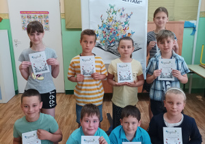 Dziewięcioro uczniów klas trzecich trzyma dyplomy uczestnictwa w konkursie.