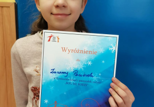Dziewczynka trzyma w ręku dyplom.