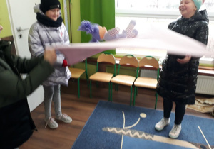 Dwie dziewczynki bujają na kocu lalkę prezentując w ten sposób zabawy dzieci na Grenlandii.