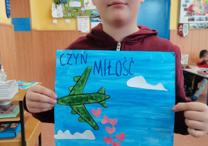 Chłopiec prezentuje wykonany przez siebie plakat.