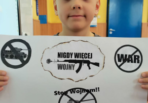 Chłopiec prezentuje wykonany przez siebie plakat.