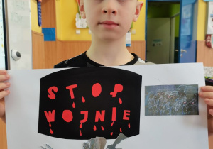 Chłopiec prezentuje wykonany przez siebie plakat.