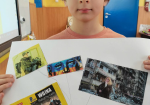 Chłopiec prezentuje wykonany przez siebie plakat.