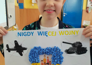 Dziewczynka prezentuje wykonany przez siebie plakat.