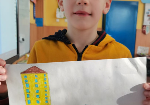 Chłopiec prezentuje wykonany przez siebie plakat.