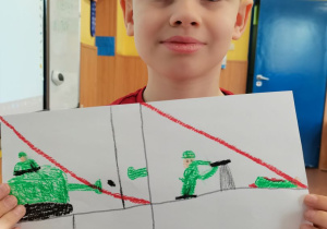 Chłopiec prezentuje wykonany przez siebie plakat.