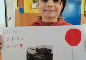 Dziewczynka prezentuje wykonany przez siebie plakat.