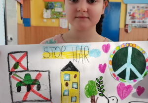 Dziewczynka prezentuje wykonany przez siebie plakat.