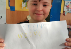 Chłopiec prezentuje wykonany przez siebie plakat.
