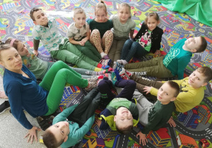 11 dzieci wraz z wychowawczynią siedzi w kole, prezentując swoje kolorowe skarpetki.