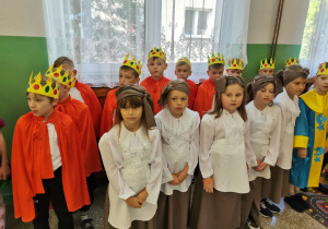 Uczniowie w swoich bajkowych strojach stoją na holu szkoły.
