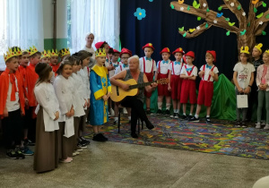 Uczniowie w swoich bajkowych strojach stoją na holu szkoły.