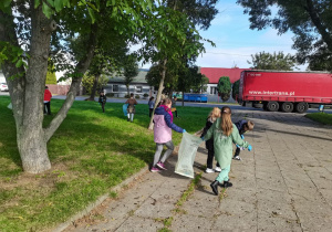 Dzieci sprzątają teren wokół szkoły.
