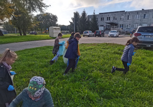 Dzieci sprzątają teren wokół szkoły.