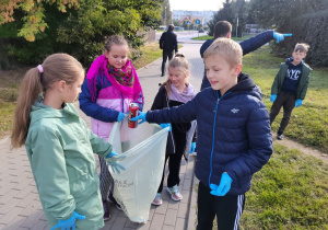 Dzieci sprzątają teren wokół szkoły.