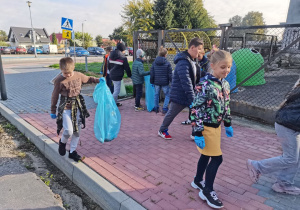 Dzieci sprzątają teren wokół szkoły.
