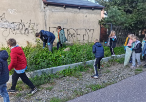 Dzieci sprzątają teren wokół szkoły.