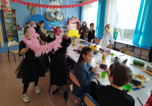 Uczniowie klasy III w strojach karnawałowych przy stole z przekąskami
