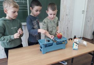Chłopcy wazą jabłko na wadze szalkowej