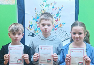 Uczniowie z klasy IIB trzymają dyplomy za udział w szkolnym konkursie "Pięknie czytam"