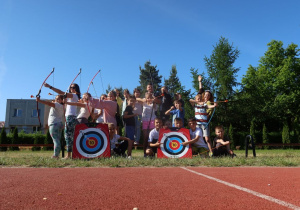 Grupa pozuje do zdjęcia z łukami i tarczami na szkolnym boisku