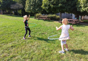 Dziewczynki kręcą kołami hula-hoop.