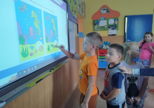 Uczniowie bawią się i uczą z wykorzystaniem tablicy dotykowej.