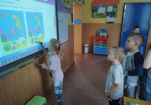 Uczniowie bawią się i uczą z wykorzystaniem tablicy dotykowej.