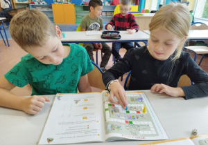 Uczniowie klasy I B grają w matematyczną grę planszową .