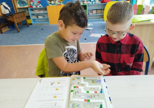 Uczniowie klasy I B grają w matematyczną grę planszową .