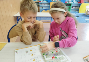Uczniowie klasy I B grają w matematyczną grę planszową .