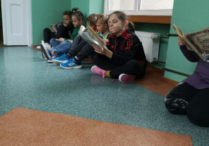 Uczniowie z klasy II B czytają lekturę podczas przerwy.