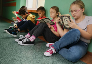 Uczniowie z klasy II B czytają lekturę podczas przerwy.