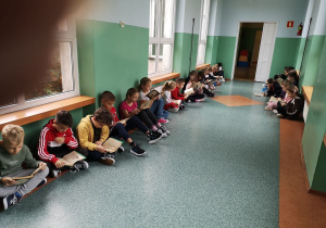Uczniowie z klasy II B czytają lekturę podczas przerwy.