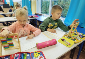 Uczniowie klasy I B liczą na liczydle.