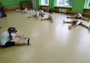Uczennica pokazuje propozycje ćwiczeń, koledzy ćwiczą.