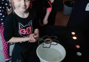 Dziecko leje wosk przez dziurkę od klucza.