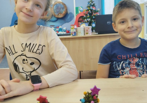 Uczniowie prezentują choinki wykonane z szyszek.