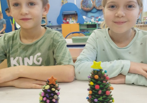 Uczniowie prezentują choinki wykonane z szyszek.