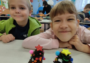 Uczniowie prezentują choinki wykonane z szyszek.