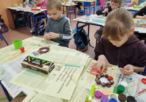 Dzieci malują świeczniki z kasztanów.