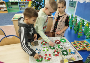 Dzieci ustawiają świeczniki z kasztanów.