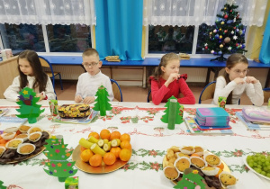 Dzieci jedzą świąteczne smakołyki i owoce