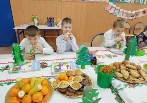 Dzieci jedzą świąteczne smakołyki i owoce