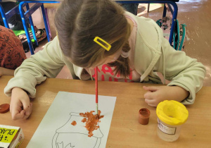 Dziecko maluje pędzelkiem za pomocą ust.