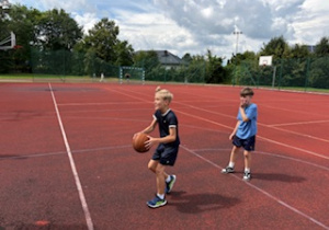 Uczestnicy półkolonii grają w piłkę na boisku szkolnym