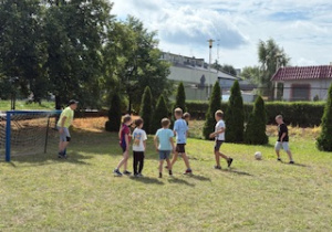 Uczestnicy półkolonii grają w piłkę na boisku