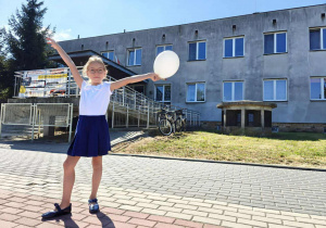 Uczennica klasy 1 b stoi przed szkołą